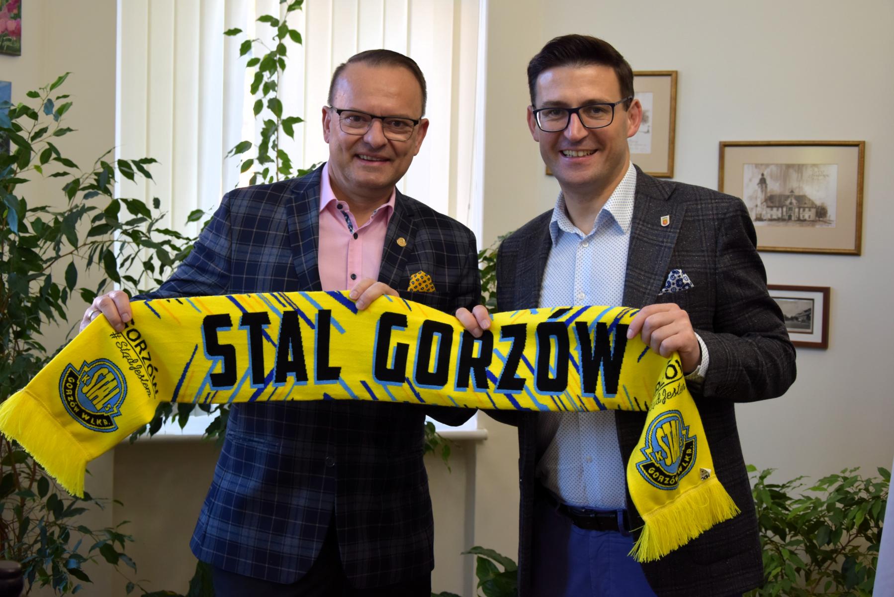 Od lewej w gabinecie stoi Wlademar Sadowski i Grzegorz Kulbicki. W dłoniach razem trzymają rozłożony żółty szalik z czarnym napisem Stal Gorzów.