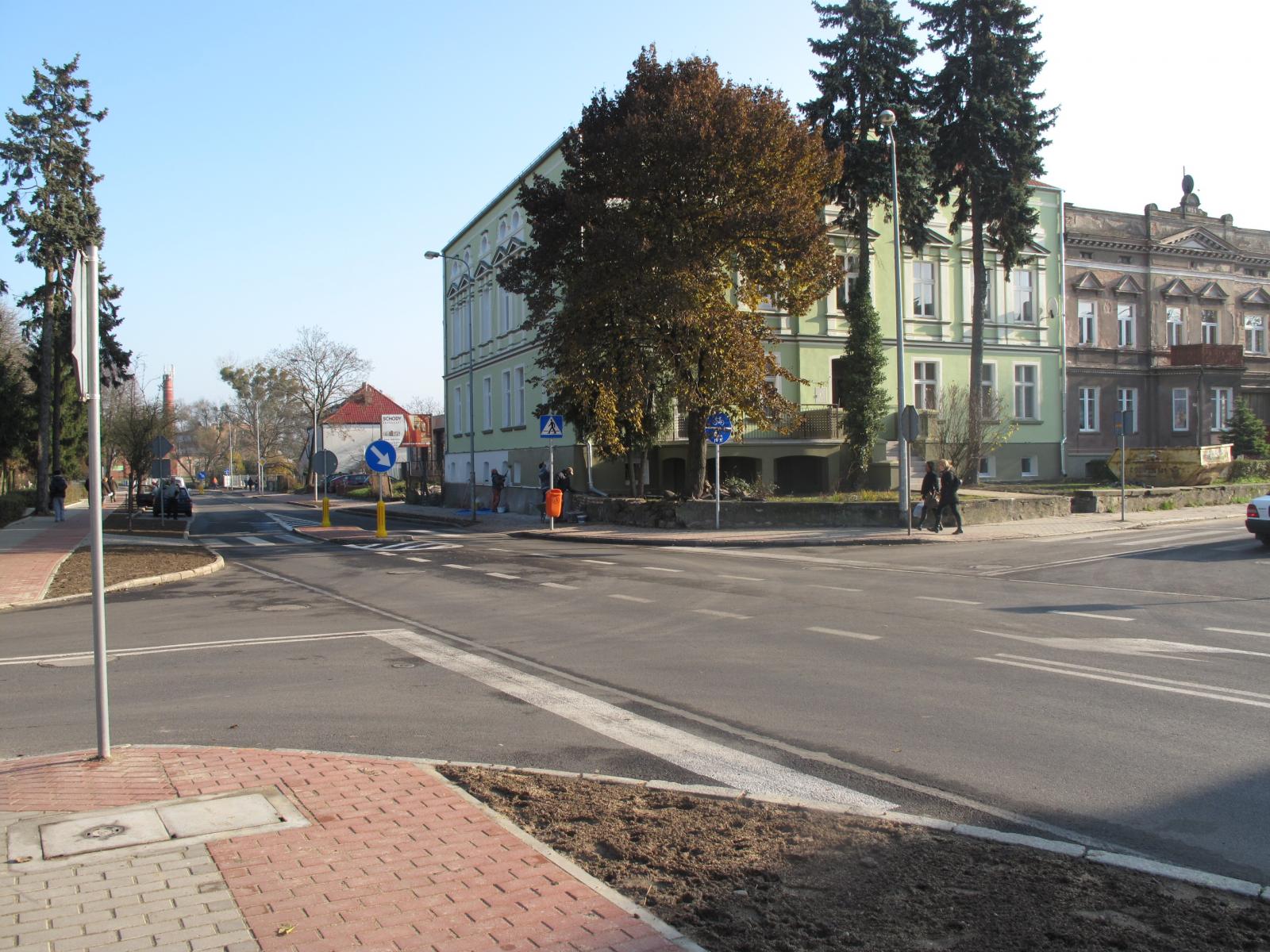 Skrzyżowanie ulic Słowackiego i Kościuszki. Widać wysepkę dla pieszych, budynki, drzewa, piesi na chodnikach